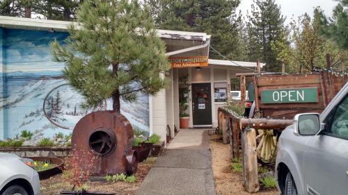 Entrance to a history museum with a mural, open sign, and rustic decor surrounded by trees.