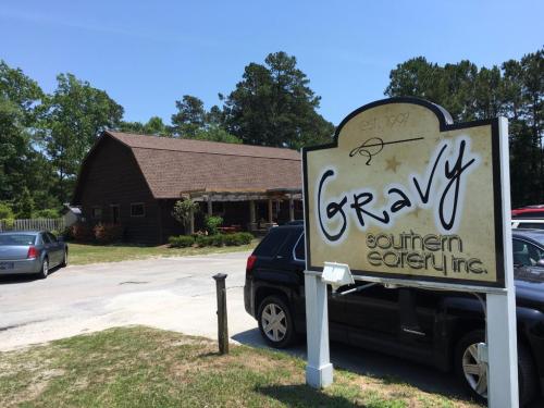 A rustic building with a sign reading "Gravy Southern Eatery Inc." surrounded by trees and parked cars.
