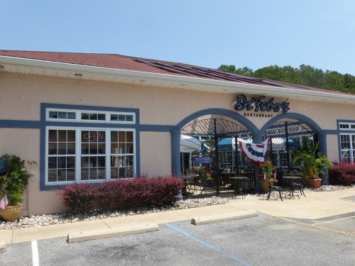 Exterior of Dr. Tebor's Restaurant, featuring a welcoming entrance, outdoor seating, and decorative plants.
