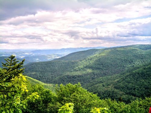 Lush green mountains under a cloudy sky, with rolling hills stretching into the distance.