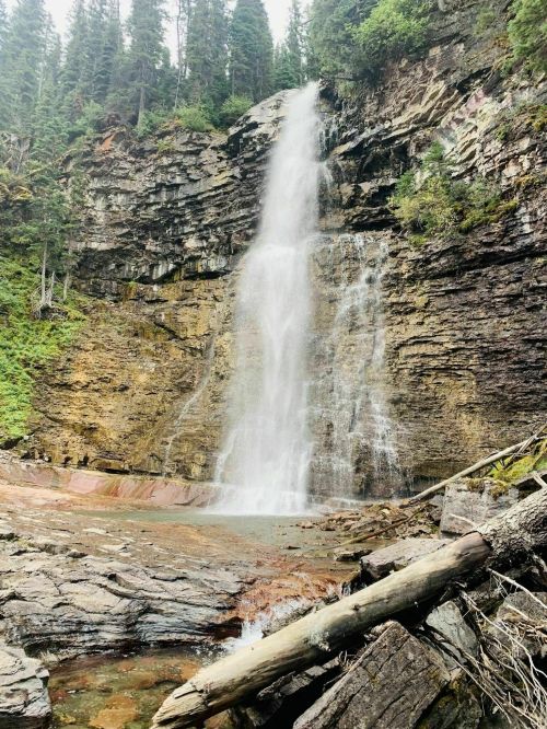 A stunning waterfall cascading down rocky cliffs, surrounded by lush green trees and a serene natural landscape.