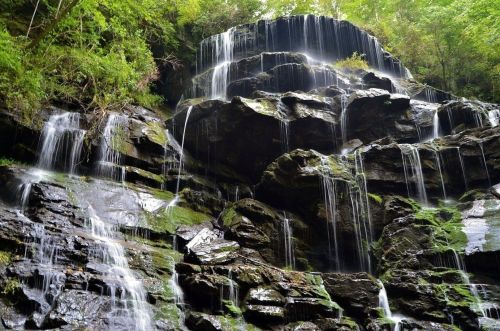 A cascading waterfall flows down rocky cliffs, surrounded by lush green foliage.