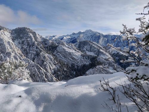 Snow-covered mountains and valleys under a clear sky, showcasing a serene winter landscape.