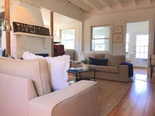 Cozy living room with beige sofas, a white brick fireplace, and natural light from large windows.