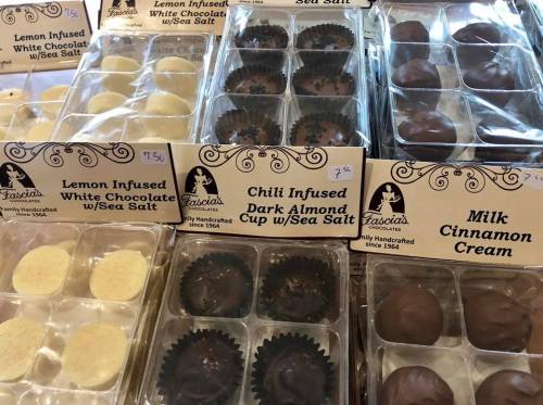 Assorted chocolates in clear packaging, labeled with flavors like lemon, chili almond, and milk cinnamon cream.