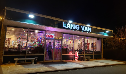 A brightly lit restaurant named "Lang Van" with festive decorations and an "Open" sign at night.