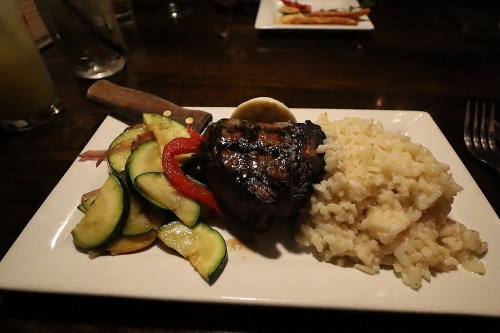 A plate featuring grilled meat with a sauce, served alongside rice and sautéed vegetables.