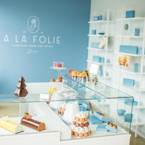 A display of colorful handmade desserts in a bright shop with blue walls and a modern design.