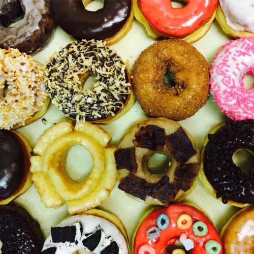 A colorful assortment of donuts, featuring various toppings like chocolate, sprinkles, and coconut, arranged neatly.
