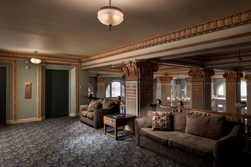 Elegant interior of a vintage lobby with plush sofas, ornate columns, and decorative lighting.