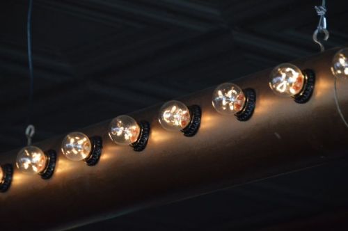 A row of vintage-style light bulbs hanging from a metallic fixture against a dark ceiling.