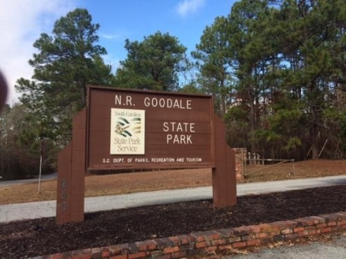 Sign for N.R. Goodale State Park in South Carolina, surrounded by trees and gravel path.