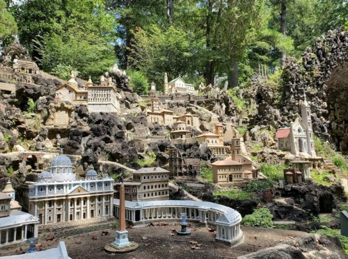 A miniature village with detailed buildings set among rocks and greenery in a natural landscape.