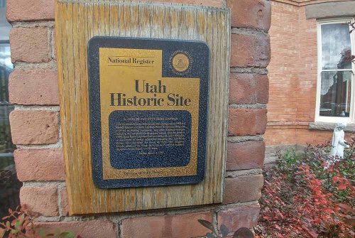 Plaque on a brick wall indicating a Utah Historic Site, featuring text about its historical significance.
