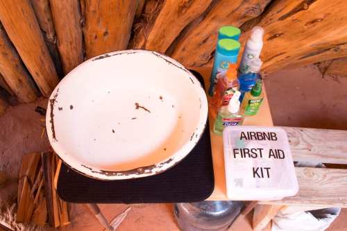 A white basin on a table with various toiletries and a labeled first aid kit beside it.