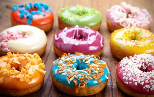 A colorful assortment of donuts with various toppings arranged on a wooden surface.
