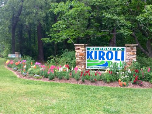 Sign welcoming visitors to Kiroli Park, surrounded by colorful flowers and greenery.