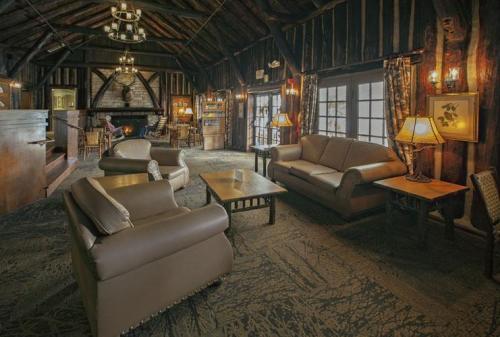 Cozy lodge interior with wooden beams, comfortable seating, a fireplace, and warm lighting.