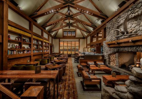 Cozy lodge interior with wooden beams, a stone fireplace, bookshelves, and comfortable seating. Warm, inviting atmosphere.