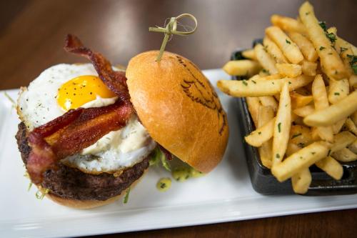 A juicy burger topped with bacon and a fried egg, served with a side of crispy fries.