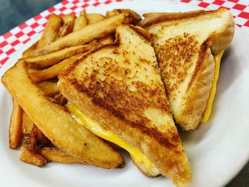 A plate of golden-brown grilled cheese sandwich slices with melted cheese, served alongside crispy French fries.