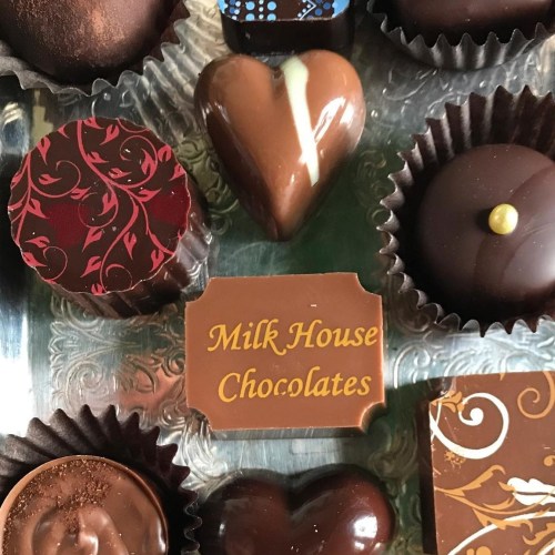 An assortment of chocolates with a label reading "Milk House Chocolates" in the center.