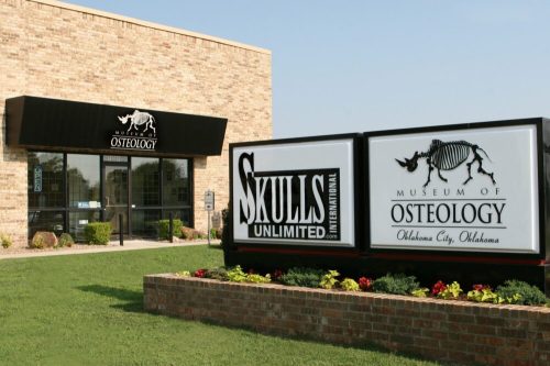 Exterior view of the Museum of Osteology in Oklahoma City, featuring a sign and a brick facade.