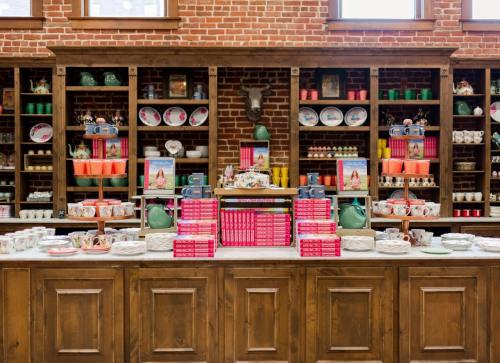 A cozy shop display featuring colorful dishware, cookbooks, and decorative items against a brick wall backdrop.
