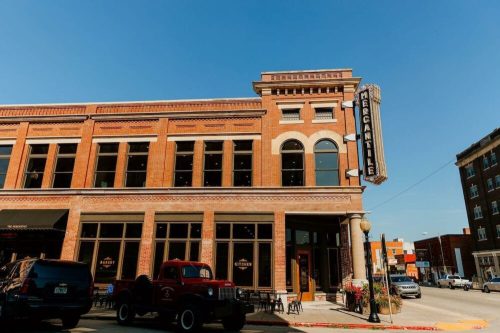 Historic brick building with a "Mercantile" sign, featuring large windows and a vintage red truck parked outside.