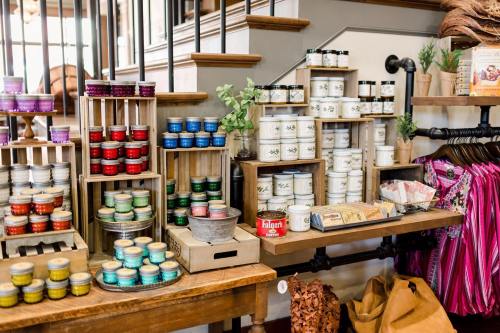 A display of colorful jars and candles on wooden shelves in a cozy shop setting.