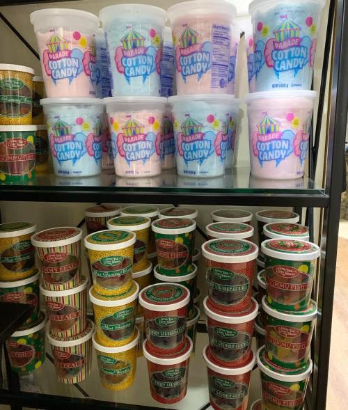 Shelves filled with colorful containers of cotton candy in various flavors and designs.