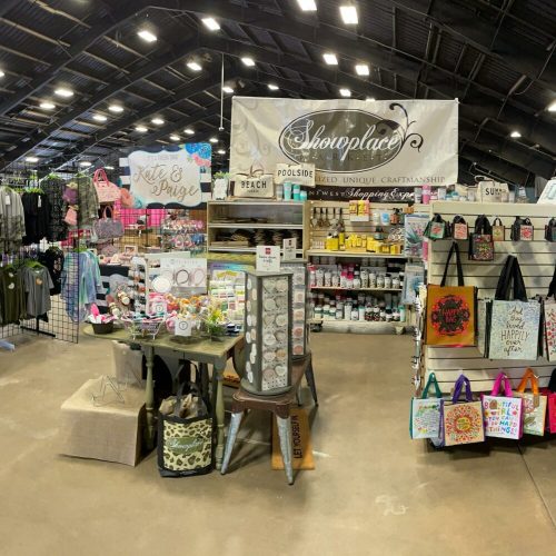 A vibrant craft fair booth displaying various handmade items, including clothing, decor, and accessories.