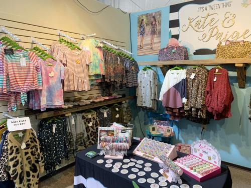 A colorful display of tween clothing featuring various tops and accessories on racks and a table with products.
