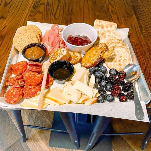 A charcuterie board with meats, cheeses, crackers, fruit, and dips arranged on a tray.