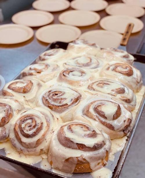 A tray of freshly baked cinnamon rolls topped with creamy icing, ready to be served.