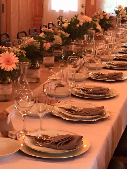 A beautifully set dining table with elegant plates, glasses, and floral centerpieces, ready for a gathering.