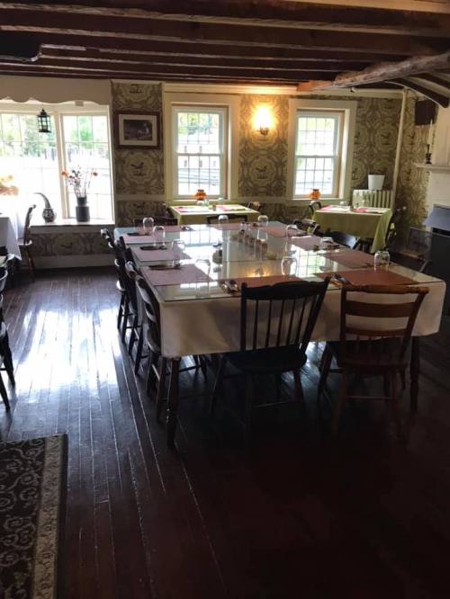 Cozy dining room with wooden floors, a large table set for a meal, and vintage decor featuring patterned wallpaper.