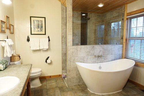 A modern bathroom featuring a freestanding tub, glass shower, and natural wood accents.