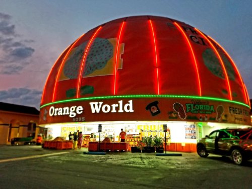 A brightly lit store called "Orange World" with a large orange dome, showcasing fresh produce and local products.