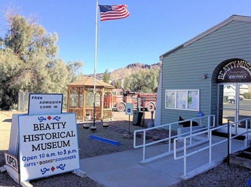 Exterior of Beatty Historical Museum with a flag, sign for free admission, and a gift shop. Open 10 a.m. to 3 p.m.