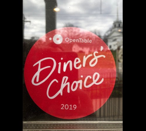 Red circular sticker featuring "Diners' Choice 2019" and the OpenTable logo, displayed on a window.