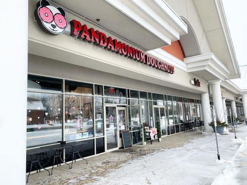 Exterior of Pandamonium Doughnuts shop, featuring a playful panda logo and a snowy sidewalk in front.