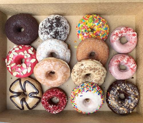 A box of assorted donuts featuring various flavors and colorful toppings, arranged in four rows.