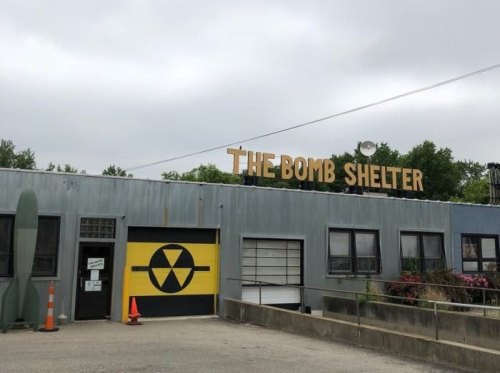 A building with a sign reading "THE BOMB SHELTER" and a yellow radiation symbol on the door.