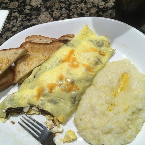 A plate with a cheese omelet, grits, and toast, served on a white dish.