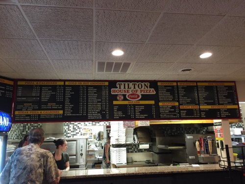 Menu board at Tilton House of Pizza displaying various food options, including pizza, calzones, and salads.
