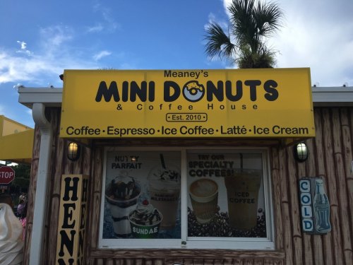 Sign for Meaney's Mini Donuts & Coffee House, featuring coffee, espresso, lattes, ice cream, and established in 2010.