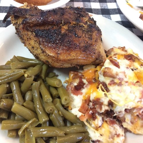 A plate of food featuring a seasoned chicken breast, green beans, and cheesy potato casserole.