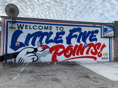 Mural on a wall reading "Welcome to Little Five Points!" with colorful lettering and a cartoon hand.