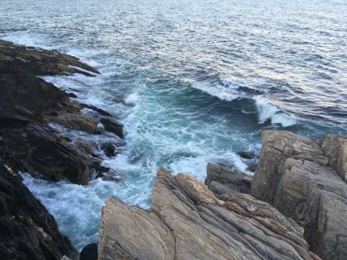 Waves crash against rocky shorelines, creating a dynamic seascape under a clear sky.